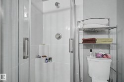 White tiled shower enclosure with a glass door and brushed chrome hardware - 