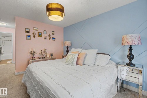 Bedroom featuring a decorative accent wall, ceiling-mounted light fixture, and plush carpet flooring - 308 10933 124 Street, Edmonton, AB 
