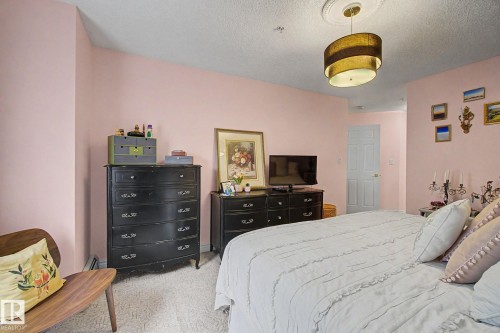 Spacious room featuring light pink walls and textured carpeting - 308 10933 124 Street, Edmonton, AB 
