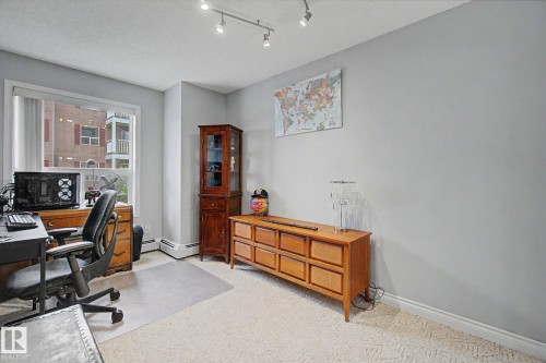Room featuring a bright window, track lighting, light-colored walls, and textured carpeting - 308 10933 124 Street, Edmonton, AB 