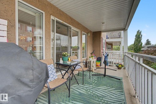 Private balcony with textured exterior, white framed windows, sliding glass door access, and a metal railing - 308 10933 124 Street, Edmonton, AB 