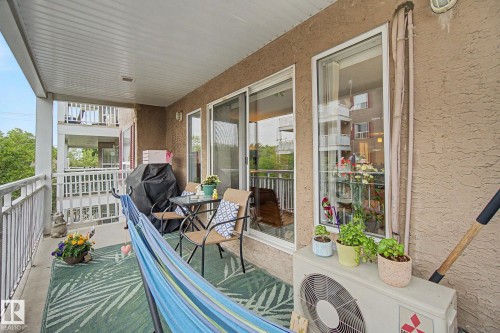 Expansive outdoor balcony featuring a textured stucco exterior, white railings, and a panelled ceiling - 308 10933 124 Street, Edmonton, AB 