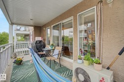 Expansive outdoor balcony featuring a textured stucco exterior, white railings, and a panelled ceiling - 