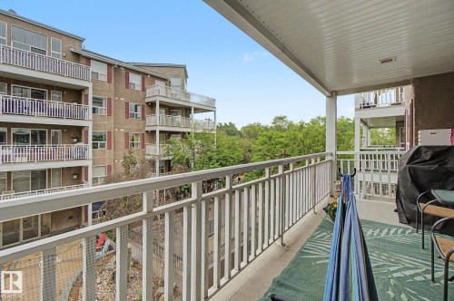 Private balcony featuring a textured exterior wall, white railing, and a matching white overhead structure - 308 10933 124 Street, Edmonton, AB 
