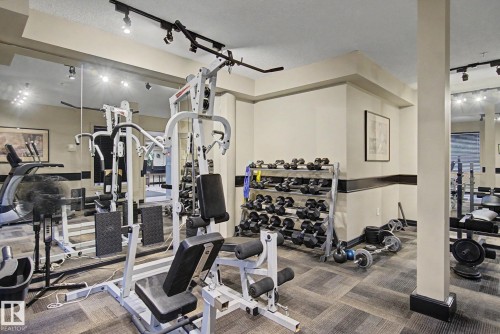 Dedicated fitness area featuring extensive mirrored walls, track lighting, and geometric carpet flooring - 308 10933 124 Street, Edmonton, AB 