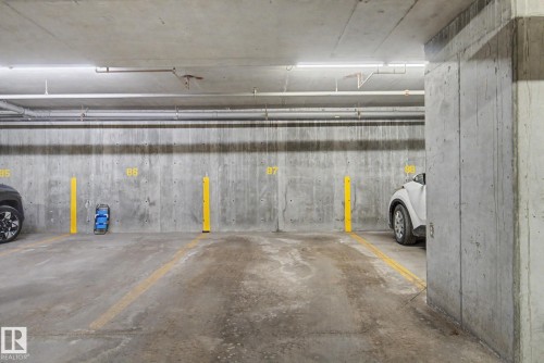 Underground parking space featuring concrete construction and overhead fluorescent lighting - 308 10933 124 Street, Edmonton, AB 