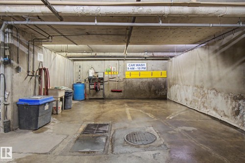 Concrete floor car wash area with exposed overhead piping, concrete block walls, and an industrial curtain system - 308 10933 124 Street, Edmonton, AB 
