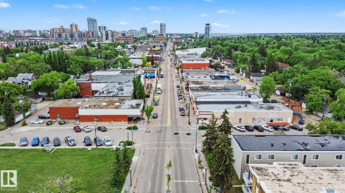 Aerial perspective of a commercial thoroughfare featuring diverse building architecture, mature trees, and urban skyline elements - 308 10933 124 Street, Edmonton, AB 