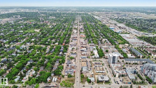 Expansive aerial perspective showcasing a developed urban landscape featuring residential areas with mature tree canopies, commercial districts, and multi-story buildings - 308 10933 124 Street, Edmonton, AB 