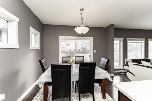 Open-concept dining area featuring dark wood-finish flooring, grey wall paint, and multiple windows with white trim - 115 57 Street, Edmonton, AB 
