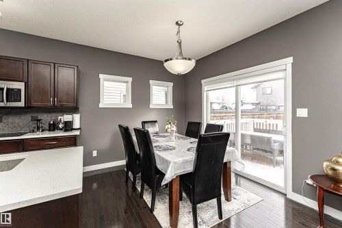 Dining area featuring rich wood-finish flooring, a contemporary ceiling fixture, and direct access to an outdoor deck through sliding glass doors - 115 57 Street, Edmonton, AB 