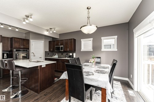 Kitchen island with white countertop, under-mount sink, and dark wood cabinetry - 115 57 Street, Edmonton, AB 
