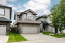 Two-story residential architecture featuring gray siding, stone facade accents, a dark shingle roof, and an attached two-car garage - 115 57 Street, Edmonton, AB 