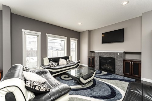 Living area featuring a fireplace with a tiled surround, integrated cabinetry, and recessed lighting - 115 57 Street, Edmonton, AB 