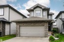 Two-story exterior featuring a stone-clad garage, gray siding, and an asphalt shingle roof - 115 57 Street, Edmonton, AB 