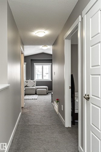 Carpeted hallway featuring contemporary lighting fixtures, light gray walls, and white trim work - 115 57 Street, Edmonton, AB 