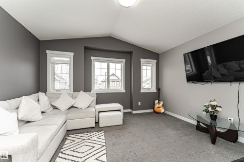 Carpeted living area featuring multiple windows, a ceiling light fixture, and neutral wall tones - 115 57 Street, Edmonton, AB 