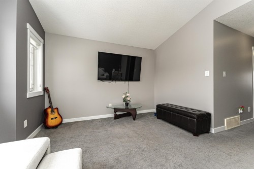 Inviting living area featuring light gray walls, plush gray carpeting, white baseboards, and a prominent window - 115 57 Street, Edmonton, AB 