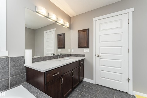 Contemporary bathroom vanity with dark wood-finish cabinetry, a light-toned countertop, and an integrated sink - 115 57 Street, Edmonton, AB 