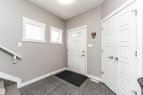 Entryway featuring grey tile flooring, white paneled doors, and a full-light entry door - 115 57 Street, Edmonton, AB 