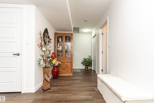 Hallway featuring wood-finish flooring, white paneled doors, and a built-in upholstered bench - 115 57 Street, Edmonton, AB 