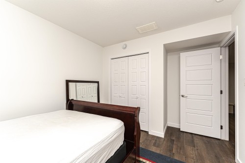 Bedroom with wood-finish flooring, crisp white walls, and a recessed ceiling vent - 115 57 Street, Edmonton, AB 