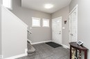 Entryway featuring gray tile flooring, a white paneled door with glass inserts, two horizontal windows with white trim, and a staircase with a gray carpet runner - 115 57 Street, Edmonton, AB 