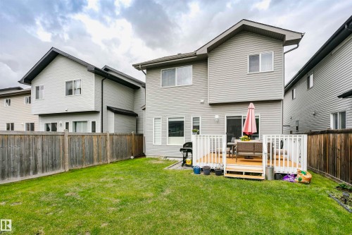 Expansive backyard featuring a green lawn, wood fence, and a raised wood deck with white railings - 115 57 Street, Edmonton, AB 