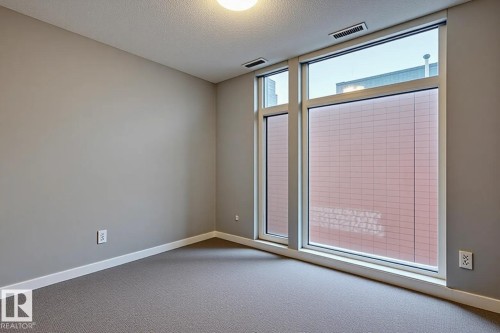Room featuring a multi-pane window with white trim, gray wall paint, white baseboards, and neutral-toned carpeting - 401 10238 103 Street, Edmonton, AB - Indoor Photo Showing Other Room