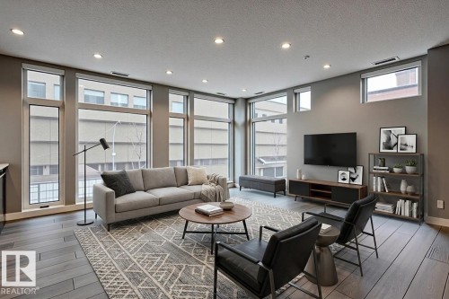 Expansive living area featuring multiple large windows, wood-finish flooring, recessed lighting, and neutral wall tones - 401 10238 103 Street, Edmonton, AB - Indoor Photo Showing Living Room