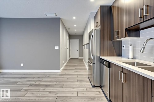 Modern kitchen featuring wood-grain cabinetry, stainless steel appliances, and a light-toned countertop - 401 10238 103 Street, Edmonton, AB - Indoor Photo Showing Kitchen With Stainless Steel Kitchen With Double Sink With Upgraded Kitchen