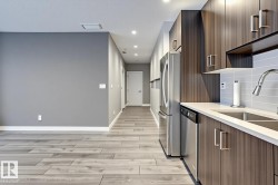 Modern kitchen featuring wood-grain cabinetry, stainless steel appliances, and a light-toned countertop - 