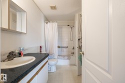 Full bathroom featuring a single vanity with dark countertop, integrated sink, and white cabinetry - 