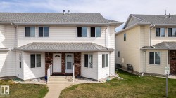 Two-story townhome featuring white siding, a contrasting brick facade accent, and a gray shingle roof - 