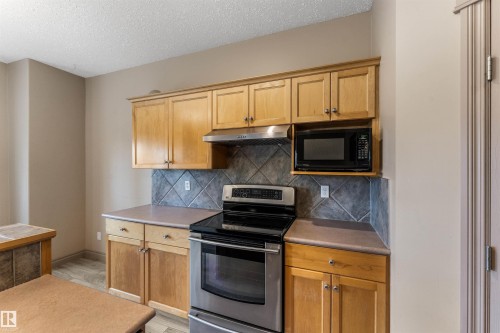 Kitchen featuring wood-finish cabinetry, a stainless steel range with a black cooktop, a built-in microwave, and a tile backsplash - 35 Oakridge Dr, St. Albert, AB - Indoor Photo Showing Kitchen