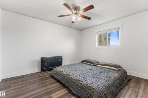 Spacious room featuring wood-finish flooring, a ceiling fan with integrated lighting, and a window with blinds - 35 Oakridge Dr, St. Albert, AB - Indoor Photo Showing Bedroom