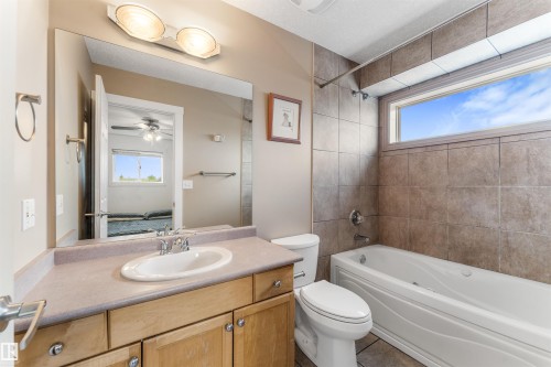Bathroom featuring a built-in vanity with a single basin sink and dual-handle faucet, a rectangular mirror, and a wall-mounted light fixture - 35 Oakridge Dr, St. Albert, AB - Indoor Photo Showing Bathroom