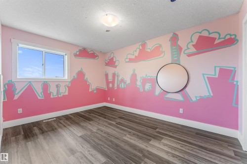 Spacious room featuring wood-finish flooring, a contemporary ceiling light fixture, and a large window with white trim - 35 Oakridge Dr, St. Albert, AB - Indoor Photo Showing Other Room