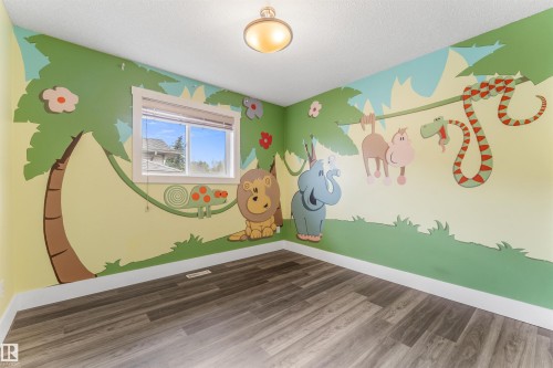 Room featuring a window with a white frame, wood-finish flooring, white baseboards, a textured ceiling, and a flush-mount light fixture - 35 Oakridge Dr, St. Albert, AB - Indoor Photo Showing Other Room