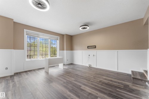 Spacious room featuring wood-finish flooring, a large multi-pane window, and white wainscoting - 35 Oakridge Dr, St. Albert, AB - Indoor Photo Showing Other Room