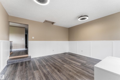 Room featuring wood-finish flooring, wainscoting, and modern flush-mount lighting fixtures - 35 Oakridge Dr, St. Albert, AB - Indoor Photo Showing Other Room