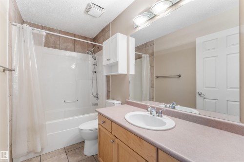 Bathroom featuring a tub/shower combination with tile surround, a single vanity with an integrated sink, and an expansive wall-mounted mirror - 35 Oakridge Dr, St. Albert, AB - Indoor Photo Showing Bathroom