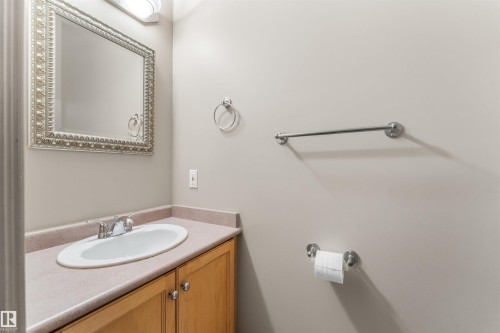 Bathroom vanity featuring a light wood-finish cabinet with silver-toned hardware, an oval undermount sink, and a countertop with an integrated backsplash - 35 Oakridge Dr, St. Albert, AB - Indoor Photo Showing Bathroom