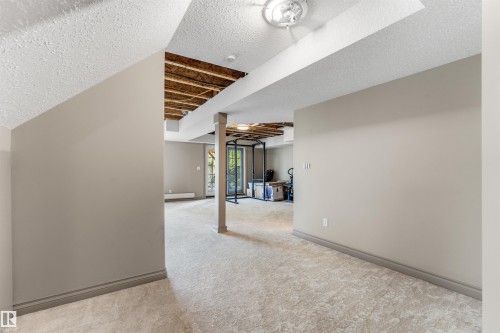 Spacious lower-level area featuring textured carpet flooring, neutral painted walls, and white trim - 35 Oakridge Dr, St. Albert, AB - Indoor Photo Showing Other Room