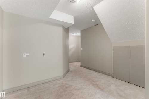 Spacious room featuring neutral paint, textured ceilings, light-toned carpeting, and built-in storage cabinets - 35 Oakridge Dr, St. Albert, AB - Indoor Photo Showing Other Room