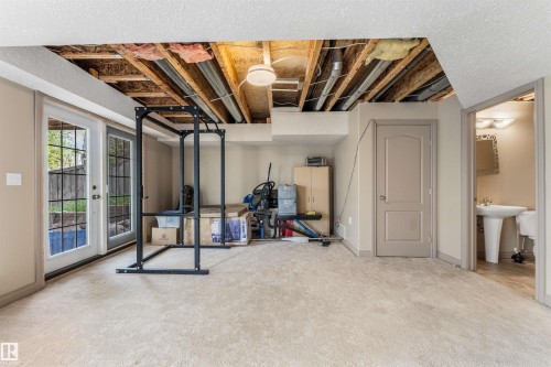 Finished space with neutral-toned carpeting, featuring exposed ceiling joists and utility lines - 35 Oakridge Dr, St. Albert, AB - Indoor Photo Showing Basement