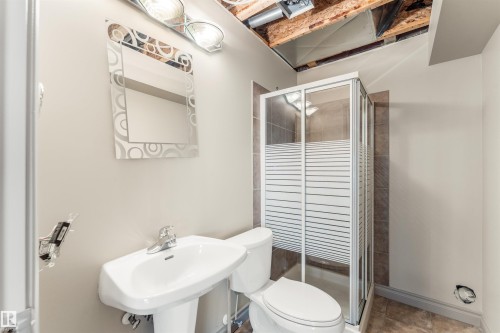 Pedestal sink with chrome faucet, toilet, and a glass-enclosed shower with frosted panels and tile surround - 35 Oakridge Dr, St. Albert, AB - Indoor Photo Showing Bathroom