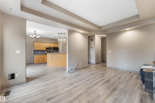 Open-concept living space with wood-finish flooring, tray ceiling, recessed lighting, and a neutral color palette - 35 Oakridge Dr, St. Albert, AB - Indoor