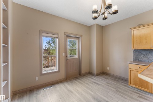 Dining area featuring wood-finish flooring, a built-in shelving unit, and a bronze-finish chandelier - 35 Oakridge Dr, St. Albert, AB - Indoor Photo Showing Other Room