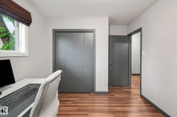 Room featuring wood-finish flooring, white walls, and a window with a woven shade - 